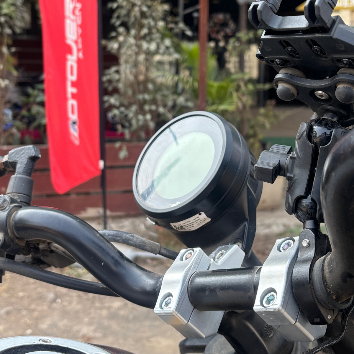 Close-up of a motorcycle handlebar with a red flag in the background