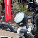 Close-up of a motorcycle handlebar with a red flag in the background